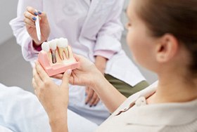Dentist pointing to a dental implant model while patient listens