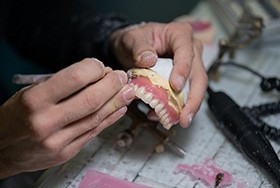 Hands carving wax gumline on dentures
