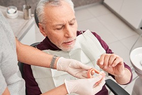Dentist handing dentures to patient in dental chair