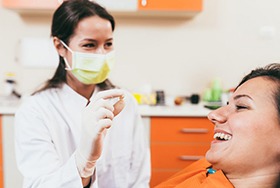Patient smiling as dentist holds their extracted tooth