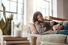 Smiling woman relaxing on couch with dog