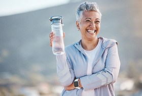 Woman smiling with water bottle on hike outside