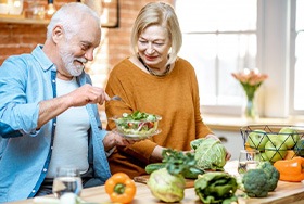 Man and woman making a salad in the kitchen