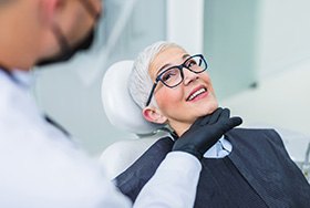 Woman with black glasses smiling at dentist