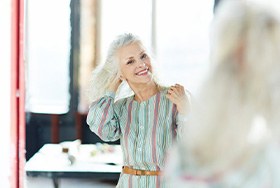 Woman playing with her hair in the mirror while getting ready