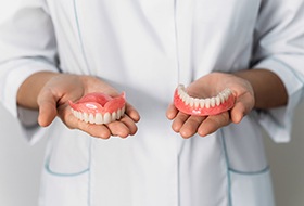 Dentist in white coat holding a row of dentures in each hand