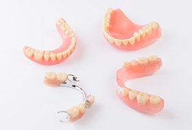 Several full and partial dentures arranged in a circle on a white surface