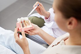 A dental patient holding a dental implant model