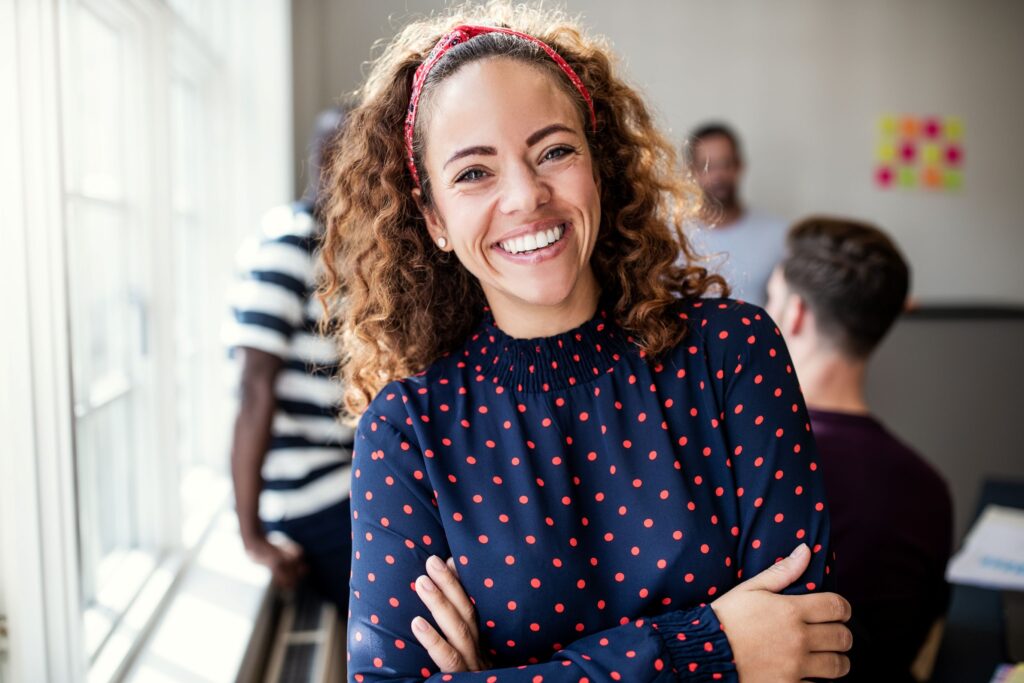 Woman in polka dotted shirt smiling with people in the background